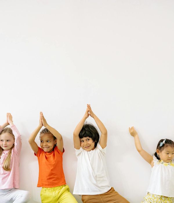 A group of children playfully attempting a yoga balance pose together.