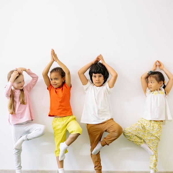 Happy child in a simple yoga pose in a colorful room.
